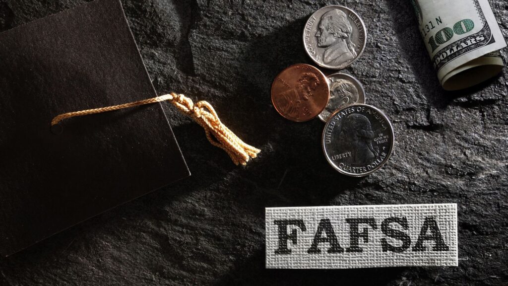 FAFA is a form of federal financial aid that community college students can use for support services. Black graduation cap with coins and a 100 dollar bill with FAFSA block letters.