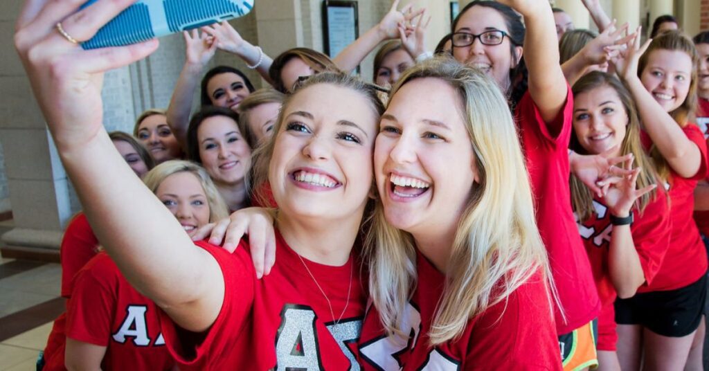 girls in red shirts, blonde hair, sorority, camera phone, group selfie, hand signs